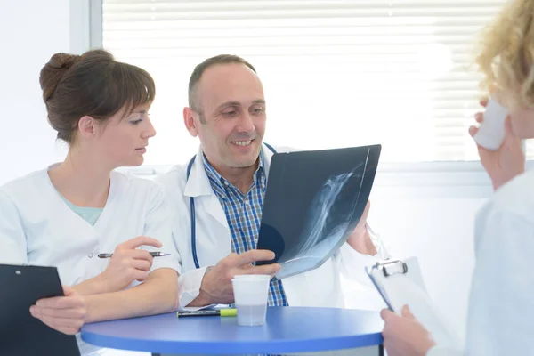 Arzt und Krankenschwestern begutachten Röntgen in der Kaffeepause — Stockfoto