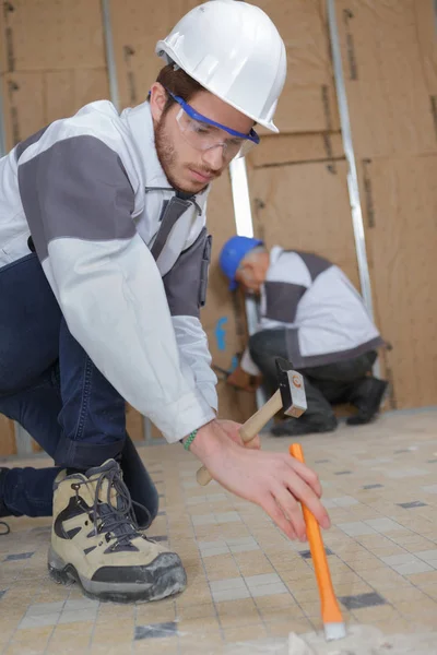 Joven trabajador de la construcción la eliminación de baldosas en el baño —  Fotos de Stock