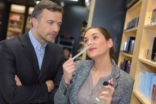 Senhora cheiro perfume, homem olhando com expressão séria — Fotografia de Stock