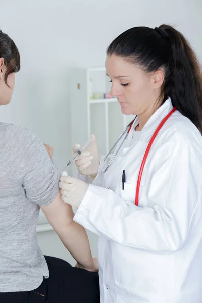 Børnelæge, der giver en injektion i armen - Stock-foto