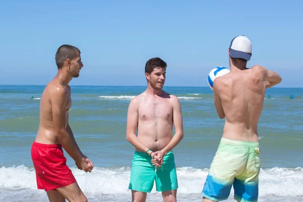 Unga män spelar på stranden — Stockfoto