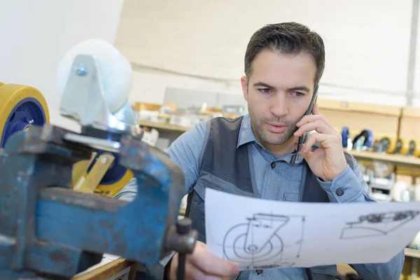 Man on telephone while looking at sketch of product — Stock Photo, Image