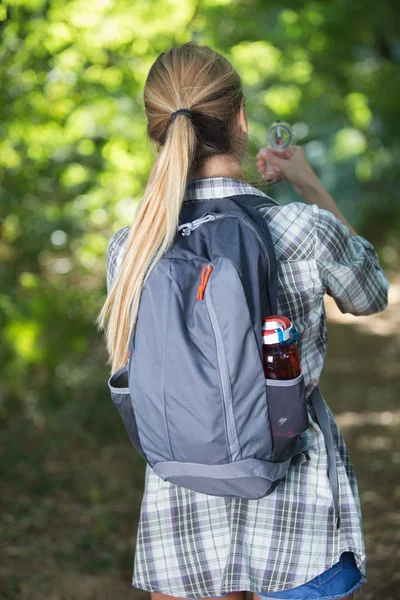 Bakifrån av kvinnliga backpacker hålla kompassen — Stockfoto