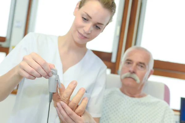 Медсестра устанавливает оксиметр для пожилого пациента в больнице — стоковое фото