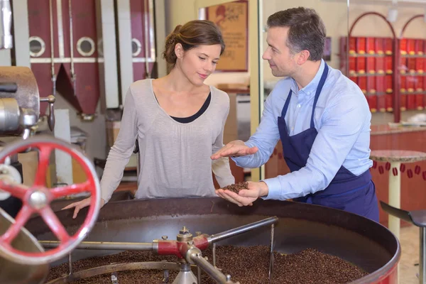 Empleado de la fábrica de café explicando tostado a visitante femenino —  Fotos de Stock