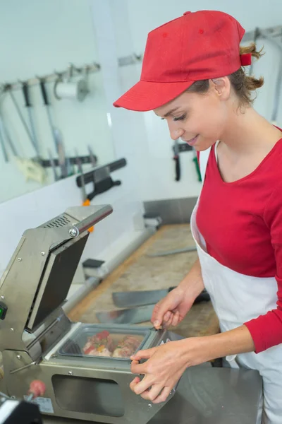 Vrouwelijke slager met spek en vlees in de teller van winkel — Stockfoto