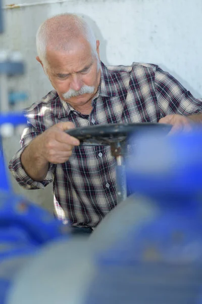 Trabalhador sênior girando roda de controle — Fotografia de Stock