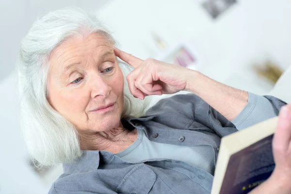 Anciana leyendo en el sofá — Foto de Stock