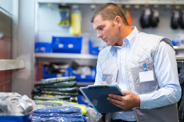 Trabajador señalando productos en el portapapeles en un almacén —  Fotos de Stock