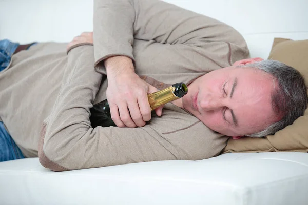 Ubriaco uomo dorme abbracciando una bottiglia di birra — Foto Stock