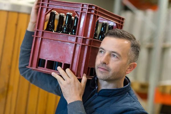 Hombre llevando una caja con botellas de vino en la tienda de vinos —  Fotos de Stock