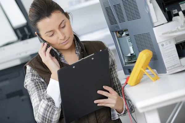 Kvindelig Tekniker Med Udklipsholder Taler Telefon - Stock-foto