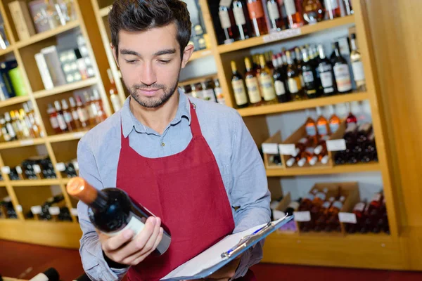 Sommelier Met Fles Wijn Staande Buurt Van Goed Gevulde Schappen — Stockfoto