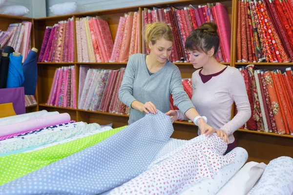 beautiful female workers choosing fabric skeins in textile shop