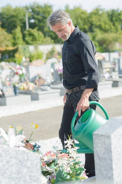 Zralý Muž Zalévání Květin Hřbitově — Stock fotografie