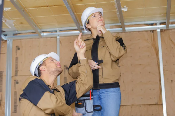 女性和男性建设者仰望天花板 — 图库照片