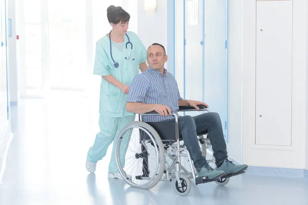 残疾男性患者轮椅的年轻女护士 — 图库照片