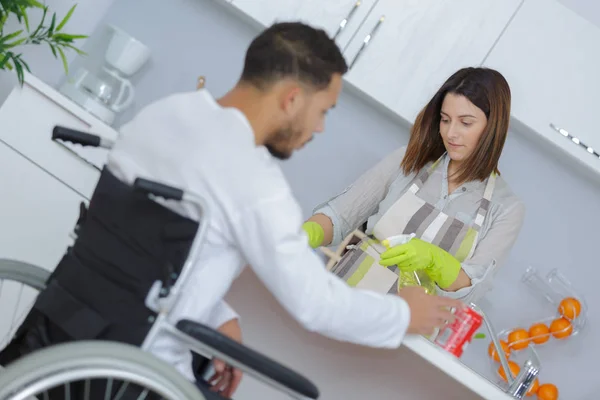 Muž Invalidním Vozíku Zatímco Přítelkyně Připravuje Jídlo — Stock fotografie