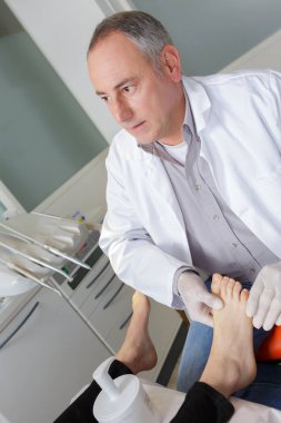 woman receives foot examination from gloved podiatrist clipart