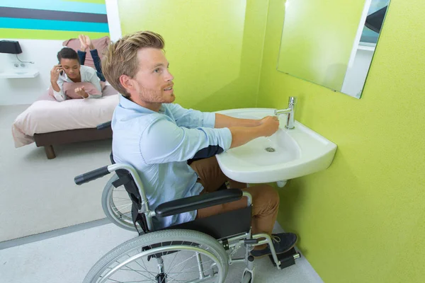 坐在轮椅上洗手的男子 — 图库照片