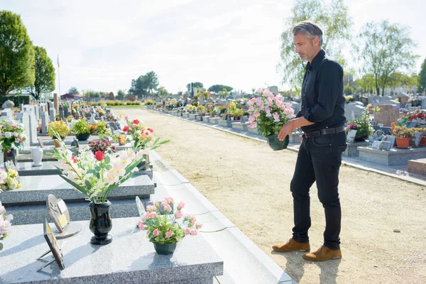 Man Graveside Holding Pot Flowers — Stock Photo, Image