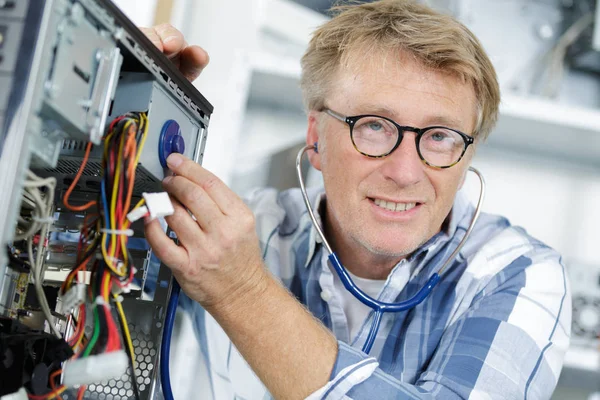 Using a stetheoscope to fix a computer — Stock Photo, Image