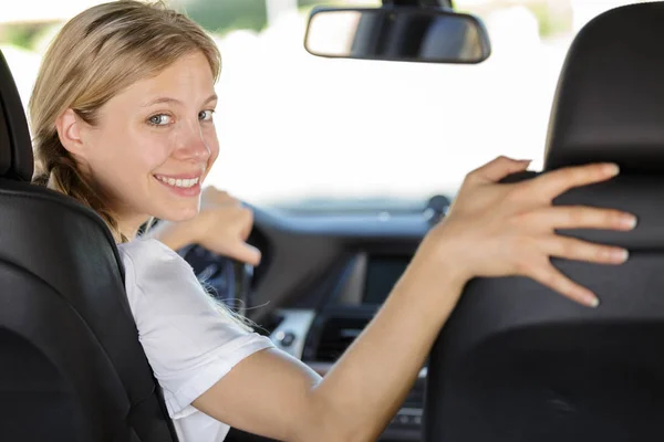 Gelukkige jonge vrouw bestuurder achteruit kijken — Stockfoto