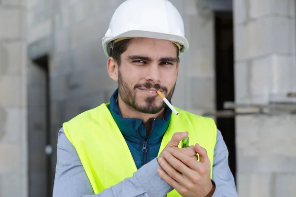 Construtor feliz fumar cigarro no local de construção — Fotografia de Stock