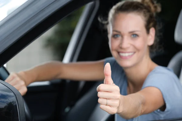 Mujer sentada en el coche y mostrando los pulgares hacia arriba — Foto de Stock