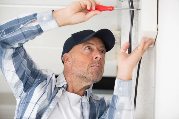 Man twists a screw into the wall — Stock Photo, Image
