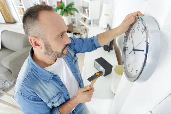Hombre con martillo colgando nuevo reloj en la pared —  Fotos de Stock