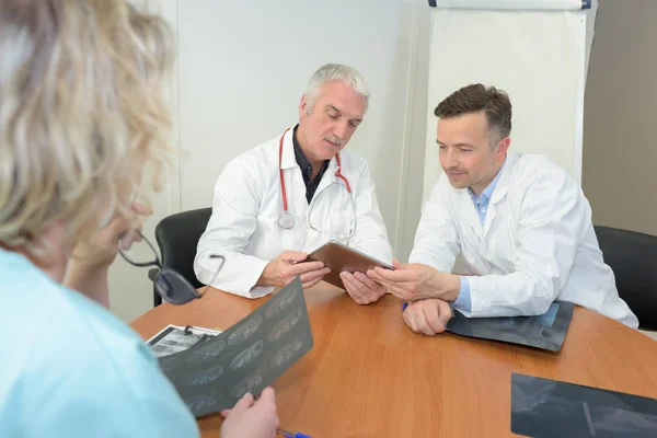 Personale medico in riunione guardando raggi X e tablet computer — Foto Stock