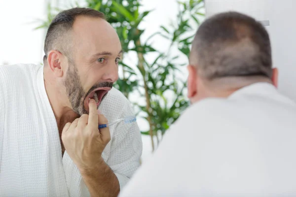 Ώριμος άνθρωπος ελέγχει τα δόντια του στον καθρέφτη — Φωτογραφία Αρχείου