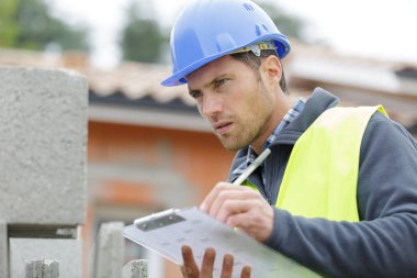 handsome builder writing on clipboard clipart