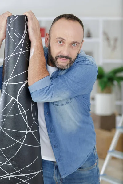 Hombre sosteniendo una alfombra durante el bricolaje — Foto de Stock