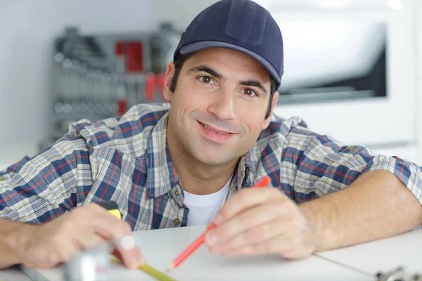 Hombre midiendo una tabla de madera — Foto de Stock