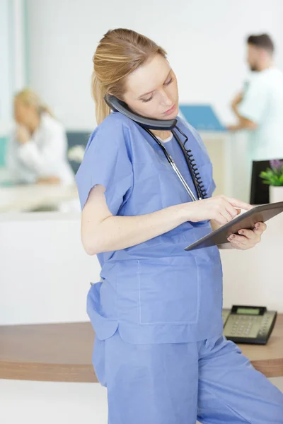 전화로 이야기하는 동안 태블릿을 사용하는 여성 의사 — 스톡 사진