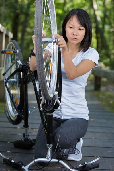 Jovem mulher fixação bicicleta fora — Fotografia de Stock