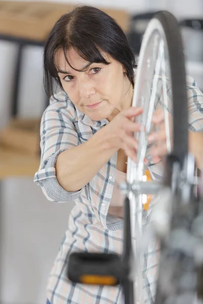 Mujer madura mirando rueda trasera de la bicicleta —  Fotos de Stock