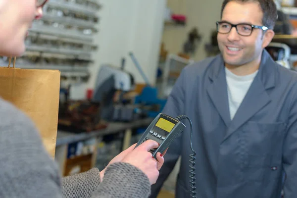 Customer entering pin code to make card payment to cobbler — Stock Photo, Image