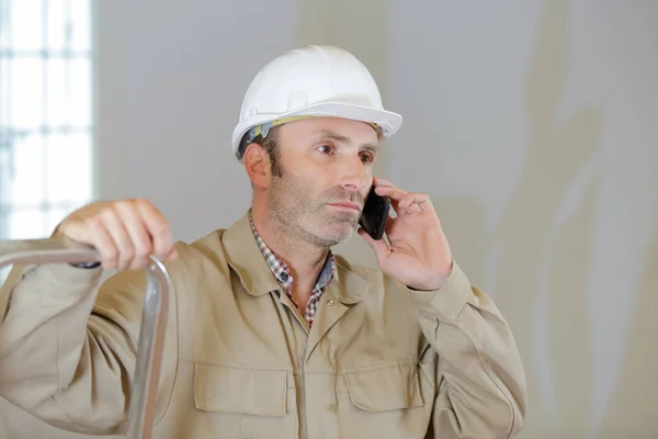 Serious male builder talking on cellphone — Stock Photo, Image