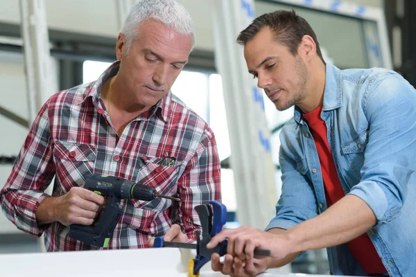 Werknemers met een boormachine en werknemers — Stockfoto