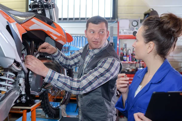 Female motorbike mechanic talking to colleague — Stock Photo, Image