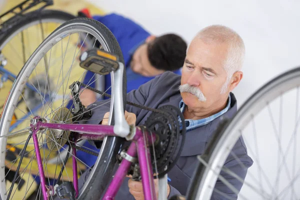 Mecânico sênior trabalhando em bicicleta — Fotografia de Stock