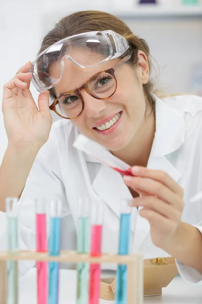 Glimlachende scheikundige die veiligheidsbril en mantel in het laboratorium zit — Stockfoto