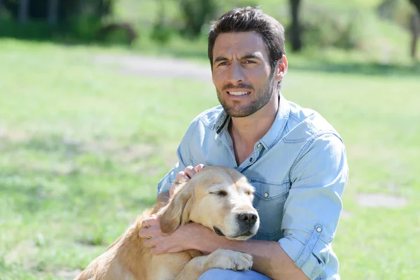 Uomo accarezzare il suo cane nel parco — Foto Stock