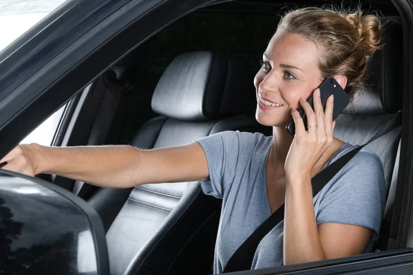 Bela jovem mulher no telefone enquanto dirigindo seu carro — Fotografia de Stock