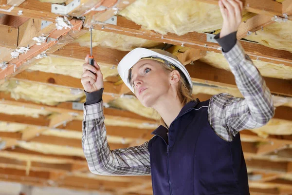 Женщина-строитель прикручивает соединительную пластину на деревянной балке — стоковое фото