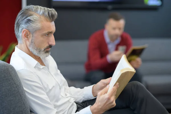 Male customer with phone waiting at hair salon — Stock Photo, Image