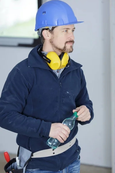 Bouwer houdt een fles water tijdens een pauze — Stockfoto